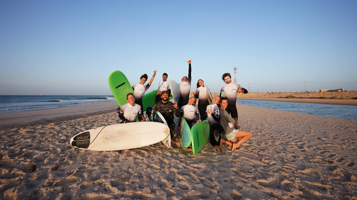 Le groupe d'une retreat pose avec ses planches sur la plage de Dakhla