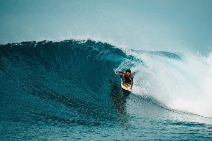 Un surfeur dans le tube d'une vague turquoise aux Mentawai