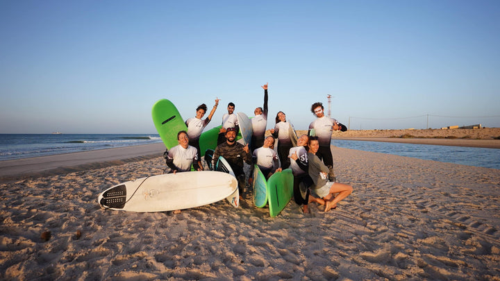 Le groupe d'une retreat pose avec ses planches sur la plage de Dakhla