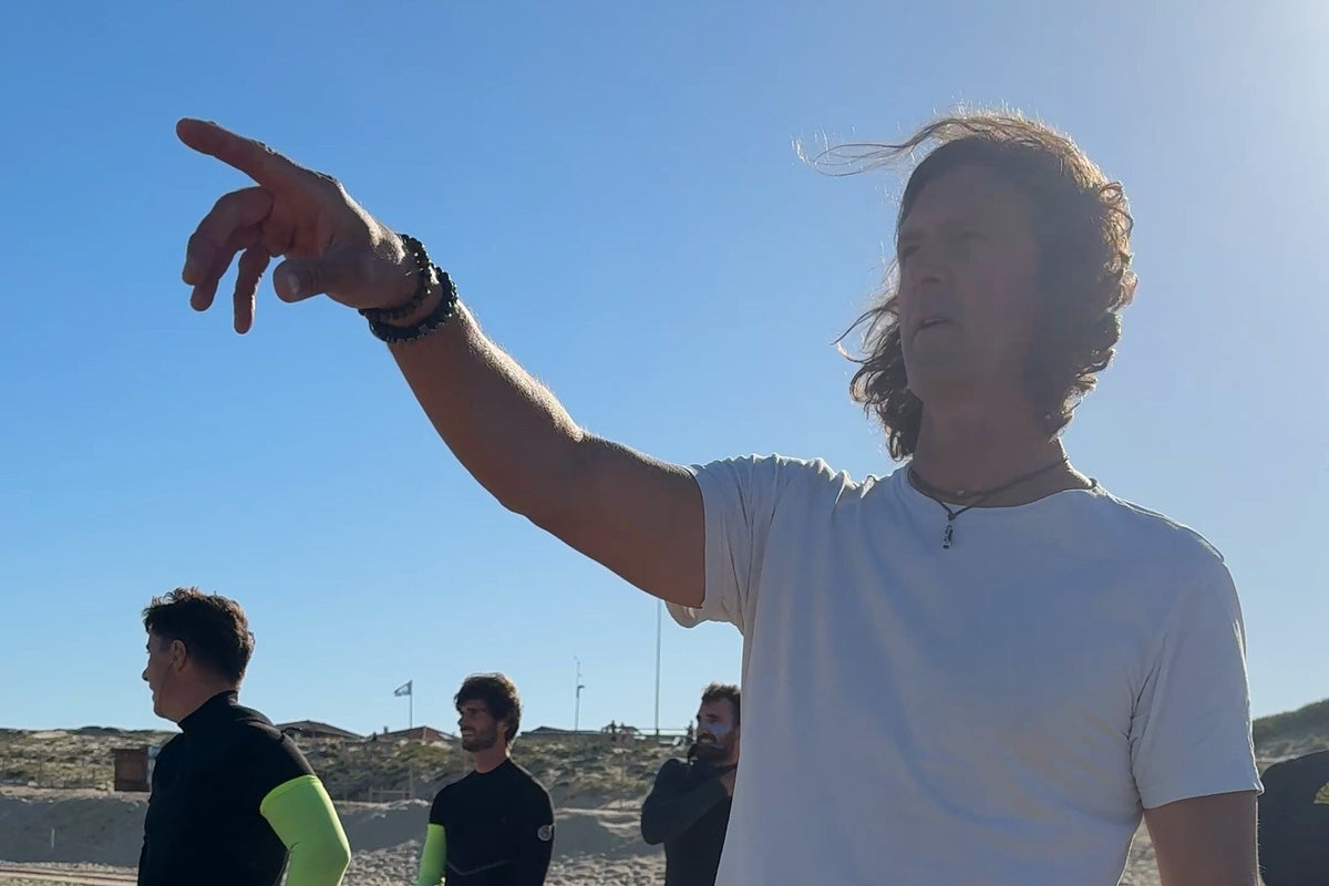 Philippe Malvaux montre les vagues à trois surfeurs sur la plage, pendant un week-end coaching