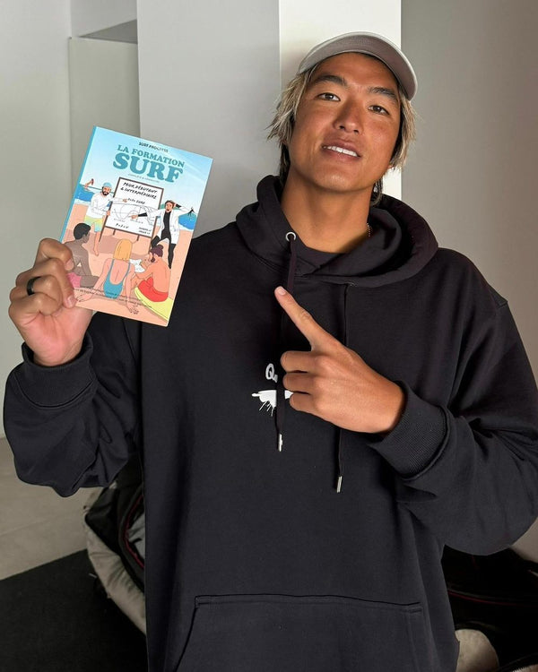 Kanoa Igarashi montre le livre La Formation Surf