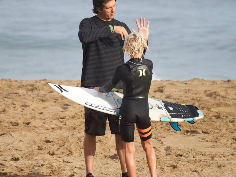 Un coach conseille une jeune surfeuse sur la plage