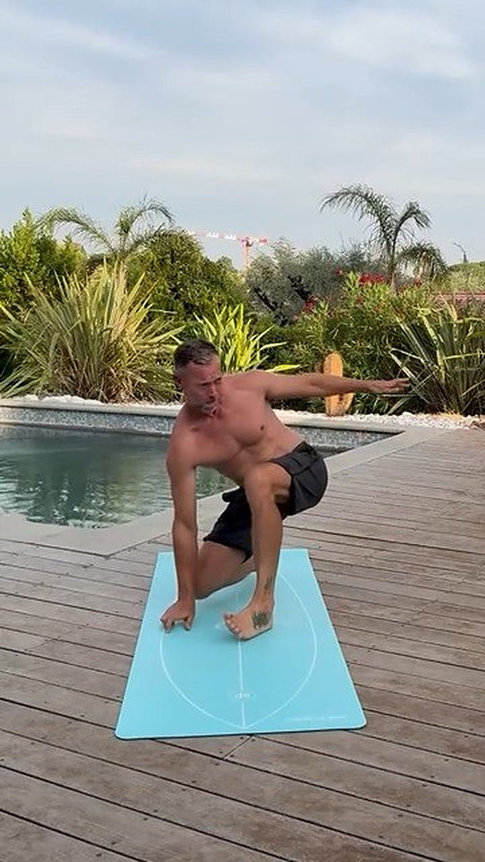 Un surfeur en position de take-off sur le tapis, au bord d'une piscine