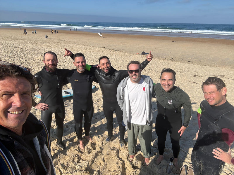 Le groupe en combinaison sur la plage à la sortie de l’eau, les vagues derrière